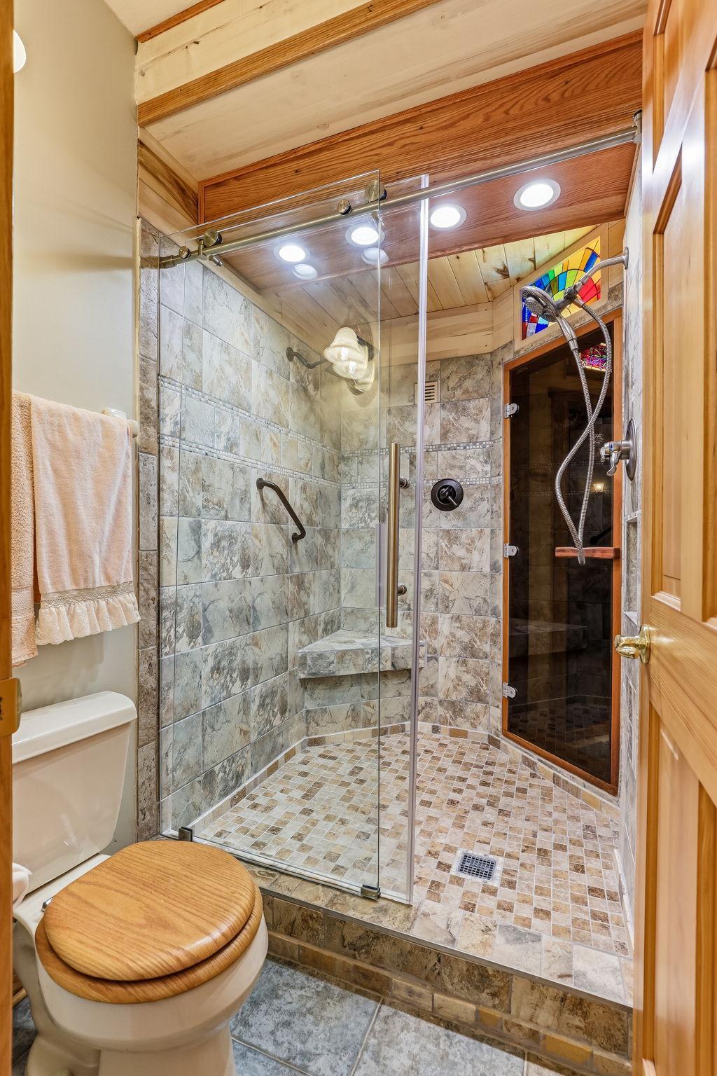 Gorgeous tiled shower with dual access from the bathroom and sauna area—offering a spa-like experience with both style and convenience.