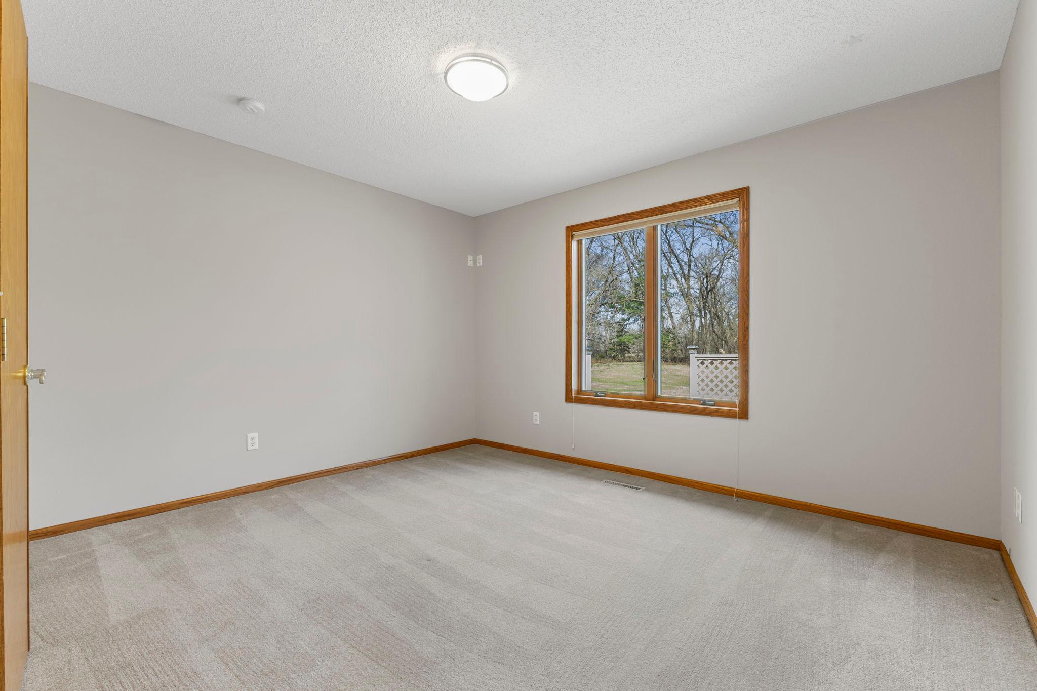 Secondary bedroom with plush carpeting, neutral tones, and abundant natural light.
