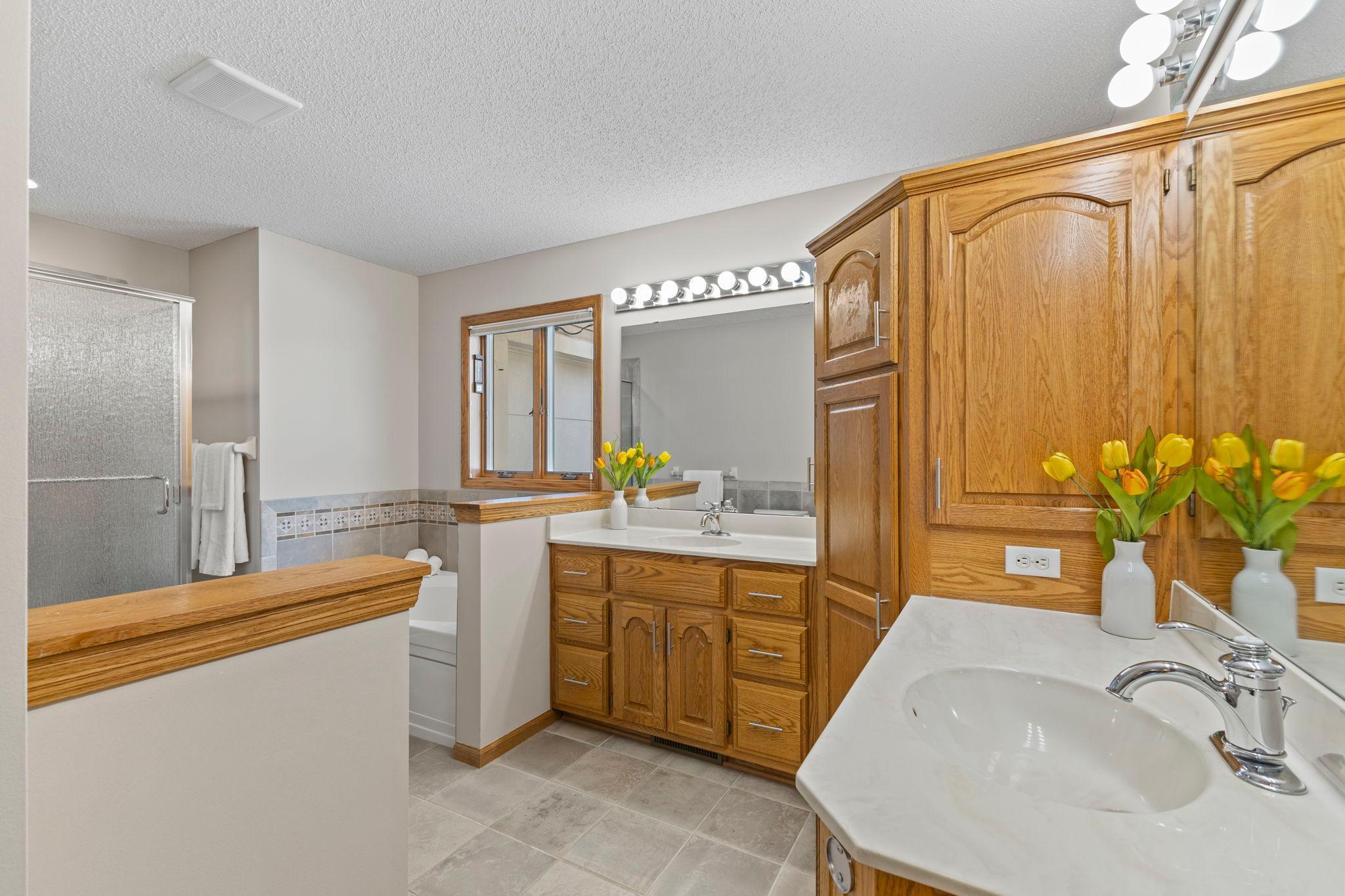 Another stunning space! This full primary bathroom boasts dual vanities, abundant storage, a jetted tub, and walk-in shower.