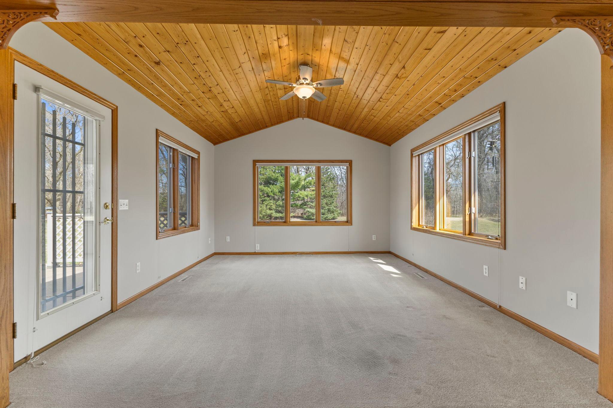 Step into the 4-season porch featuring wood ceilings, windows on each wall, and a ceiling fan for added comfort.