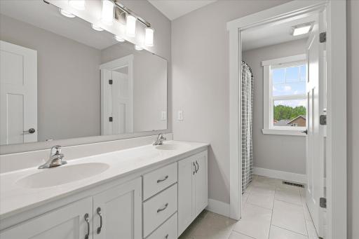 Upstairs full bathroom has a door separating the tub and toilet from the double vanity.