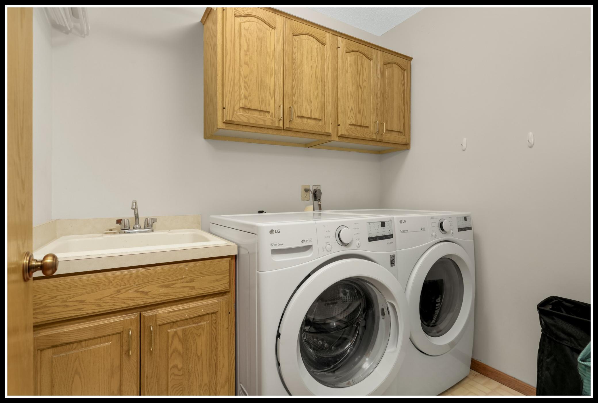 Convenient main level laundry room with cabinet storage and utility sink
