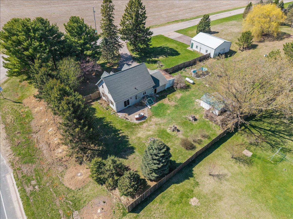 Partially fenced yard with mature trees and perennial gardens.