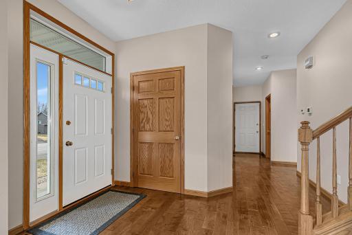 Foyer area with side window off front door, closet for outerwear and beautiful hardwood flooring.