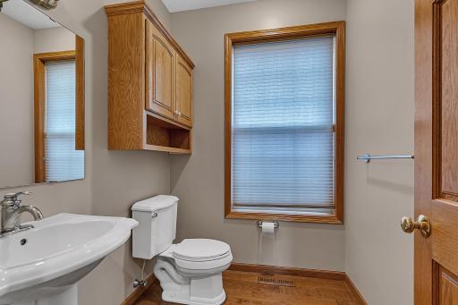 Main level half bath includes a pedestal sink, recessed lighting, and a custom linen cabinet above the toilet.
