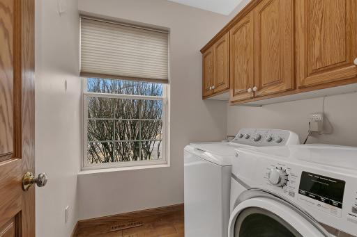 Main level laundry room with a utility sink, GE washer and dryer and upper cabinetry for storage.