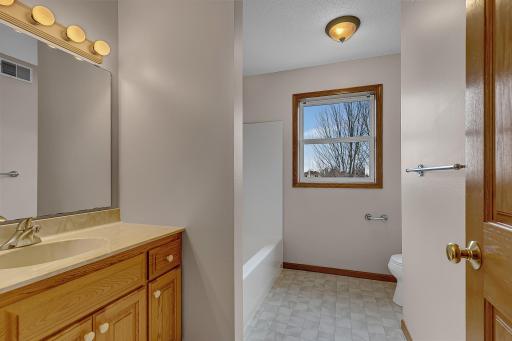 Upper level full bathroom with a raised oak vanity and an additional hallway linen closet for storage.