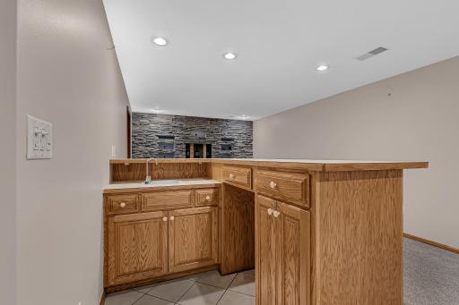 The wet bar features custom cabinetry, a sink, and recessed lighting that makes this space ideal for entertaining.