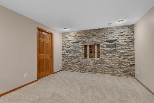 The media area features recessed lighting, surround sound speaker wiring, and a stunning stone accent wallâperfect for a mounted TV or projector setup.