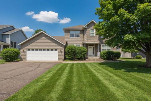 Beautiful home featuring new vinyl siding, decorative cinderblock foundation accents, an asphalt driveway, and fully landscaped grounds highlighted by poured colored and stamped concrete landscape edging.