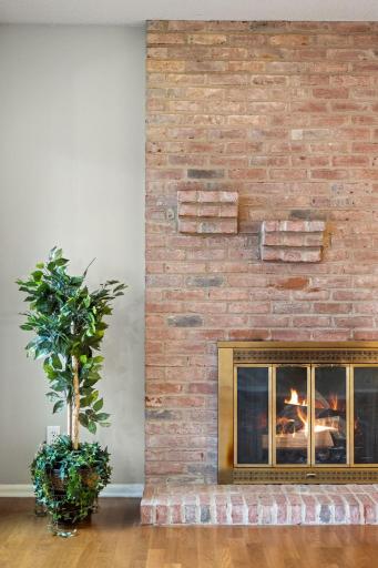 Close-up of the wood-burning fireplace with classic brick surround and hearth.