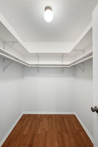 Walk-in closet with built-in shelving and hanging space for added storage.