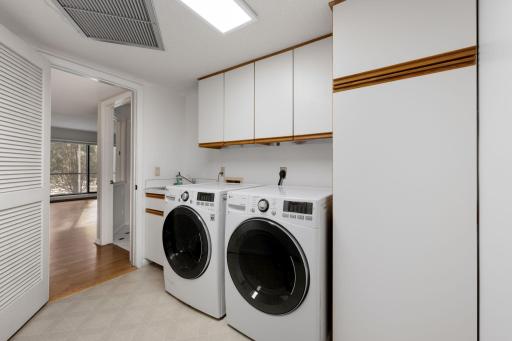 Updated In-unit laundry area with cabinetry and side-by-side washer and dryer.