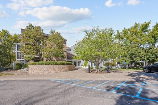 Front exterior of the building with guest parking and mature landscaping.