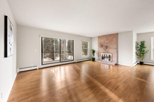 Spacious living room with hardwood floors, oversized windows, and a beautiful brick wood burning fireplace.