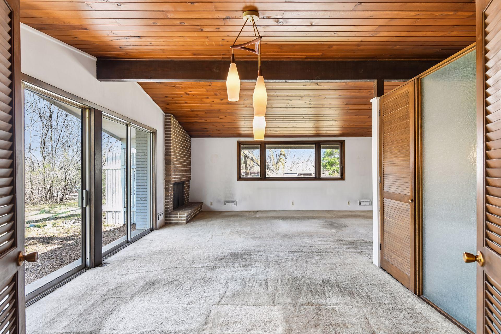 Living room/dining room with brick fireplace and a wall of patio doors to back yard.