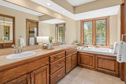 Private primary bathroom suite with double vanity sinks and cupboards, bathtub and separate shower.