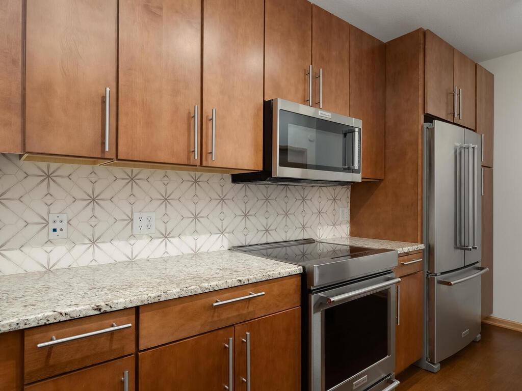 This incredible kitchen boasts a breathtaking backsplash adorned with light granite countertops, complemented by high-end appliances, including an induction range.