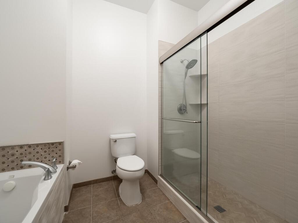 The primary bathroom suite boasts a wet room with a walk-in shower and a spacious soaking tub.