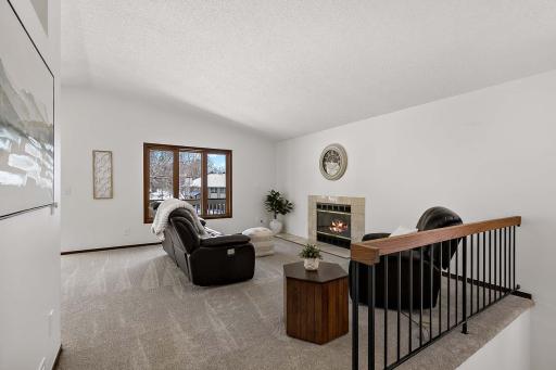 Spacious living room featuring a gas fireplace, vaulted ceiling, and abundant natural light.