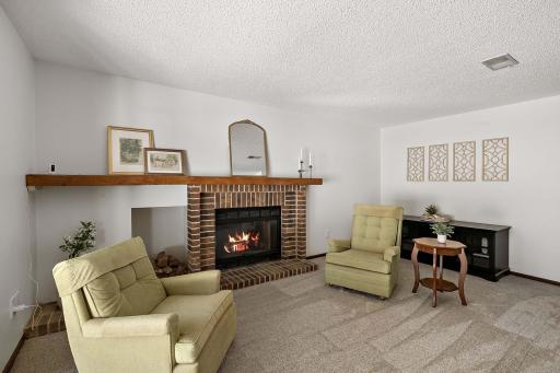 Lower-level family room with abundant natural light, a wood-burning brick fireplace, and a sliding door leading to the patio.