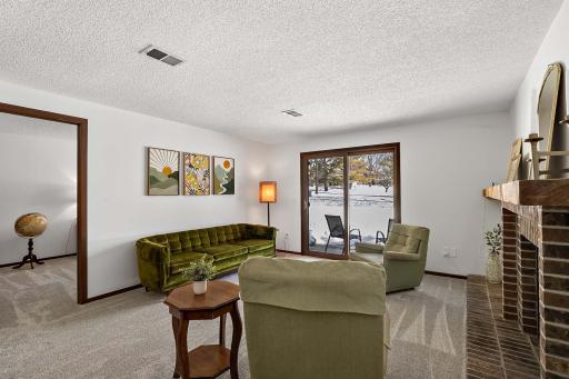 Lower-level family room with abundant natural light, a wood-burning brick fireplace, and a sliding door leading to the patio.