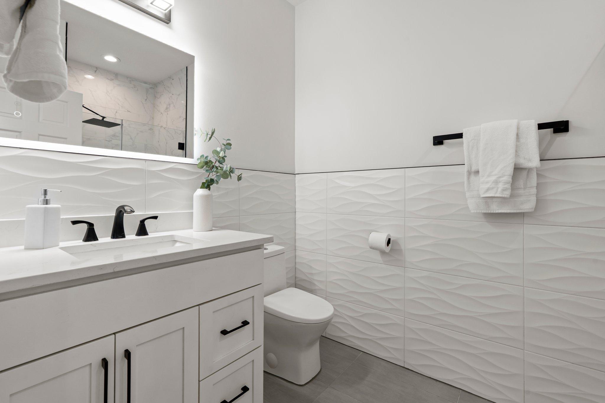 The main-level ¾ bathroom showcases a tiled walk-in shower, combining modern design with practical elegance for guests or everyday use.