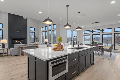 A quartz island countertop is the kitchenâs centerpiece, offering durability, sophistication, ample workspace, storage, and casual dining. The dishwasher is concealed behind custom cabinet panels to maintain a clean design.