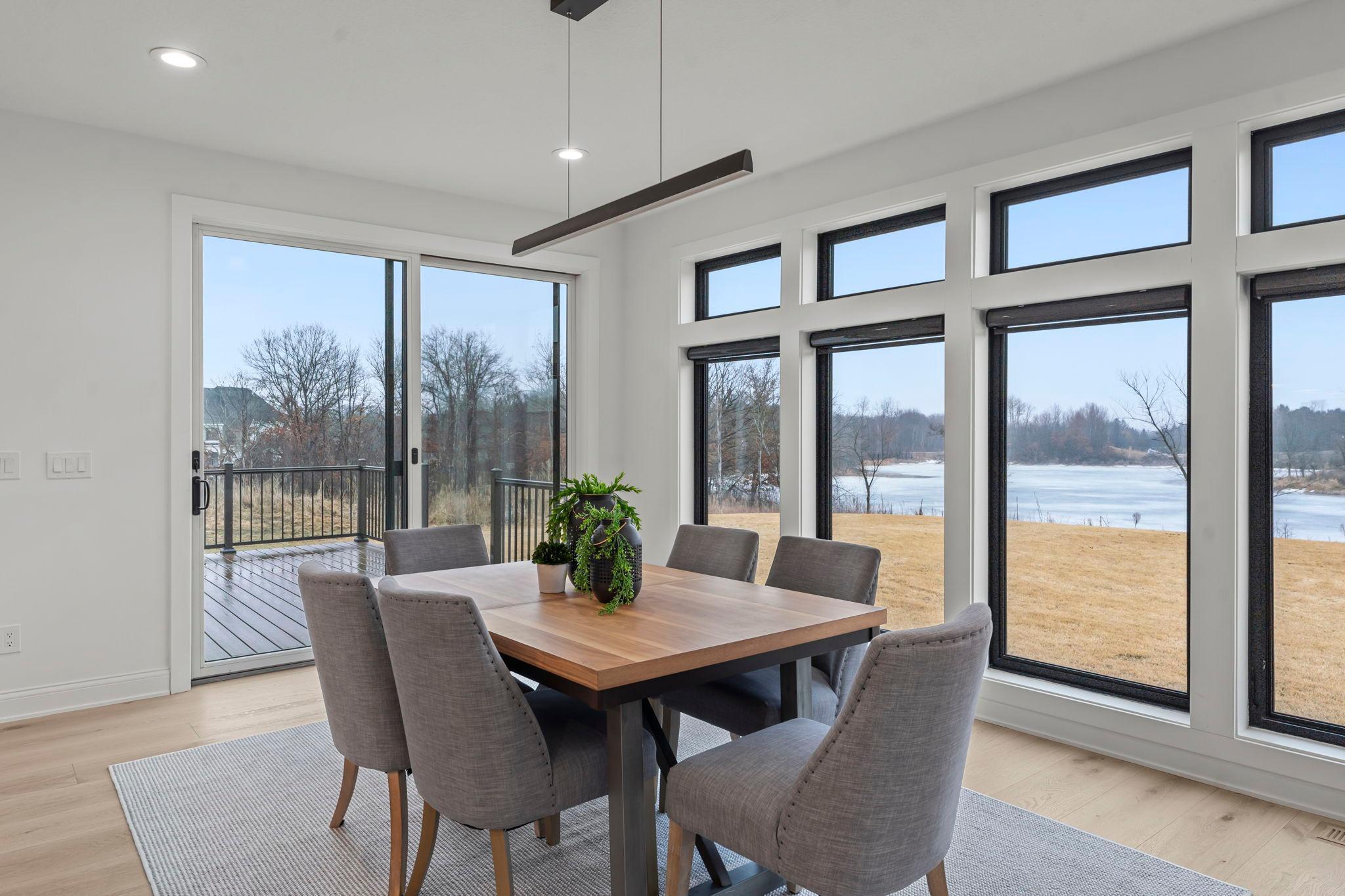 The dining room features expansive windows that flood the main floor with natural light, enhancing the open, airy feel while seamlessly connecting it to the surrounding living spaces.