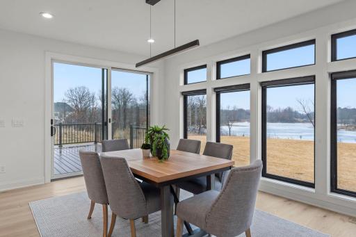 The dining room features expansive windows that flood the main floor with natural light, enhancing the open, airy feel while seamlessly connecting it to the surrounding living spaces.