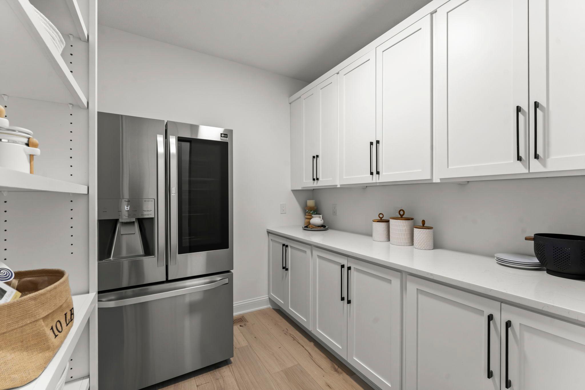 The walk-in pantry offers exceptional storage and convenience, complete with a full-size refrigerator, ample counter space and shelving to keep everything organized.