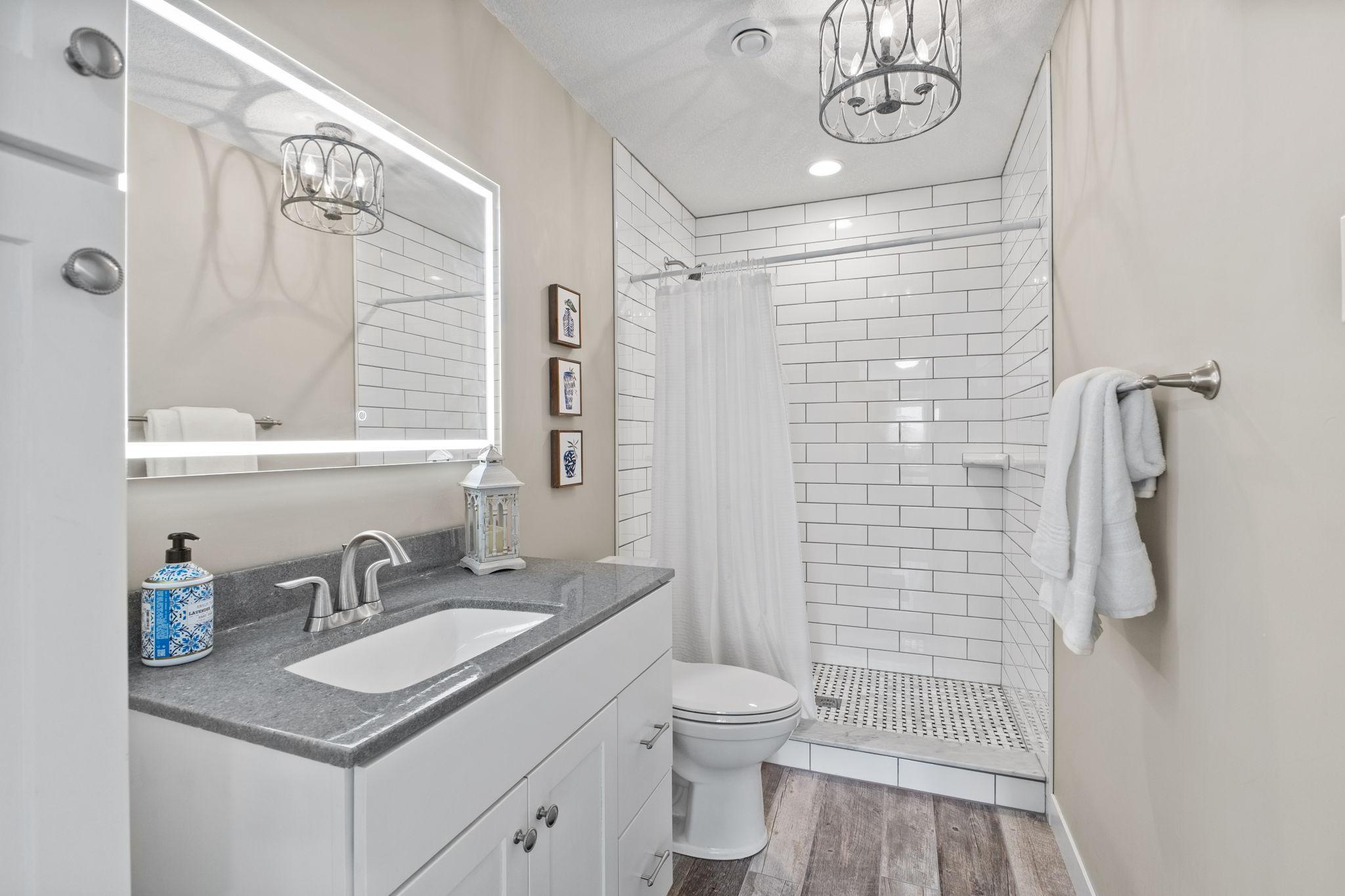 Enjoy the custom lower bathroom with designer tile, light & mirror!