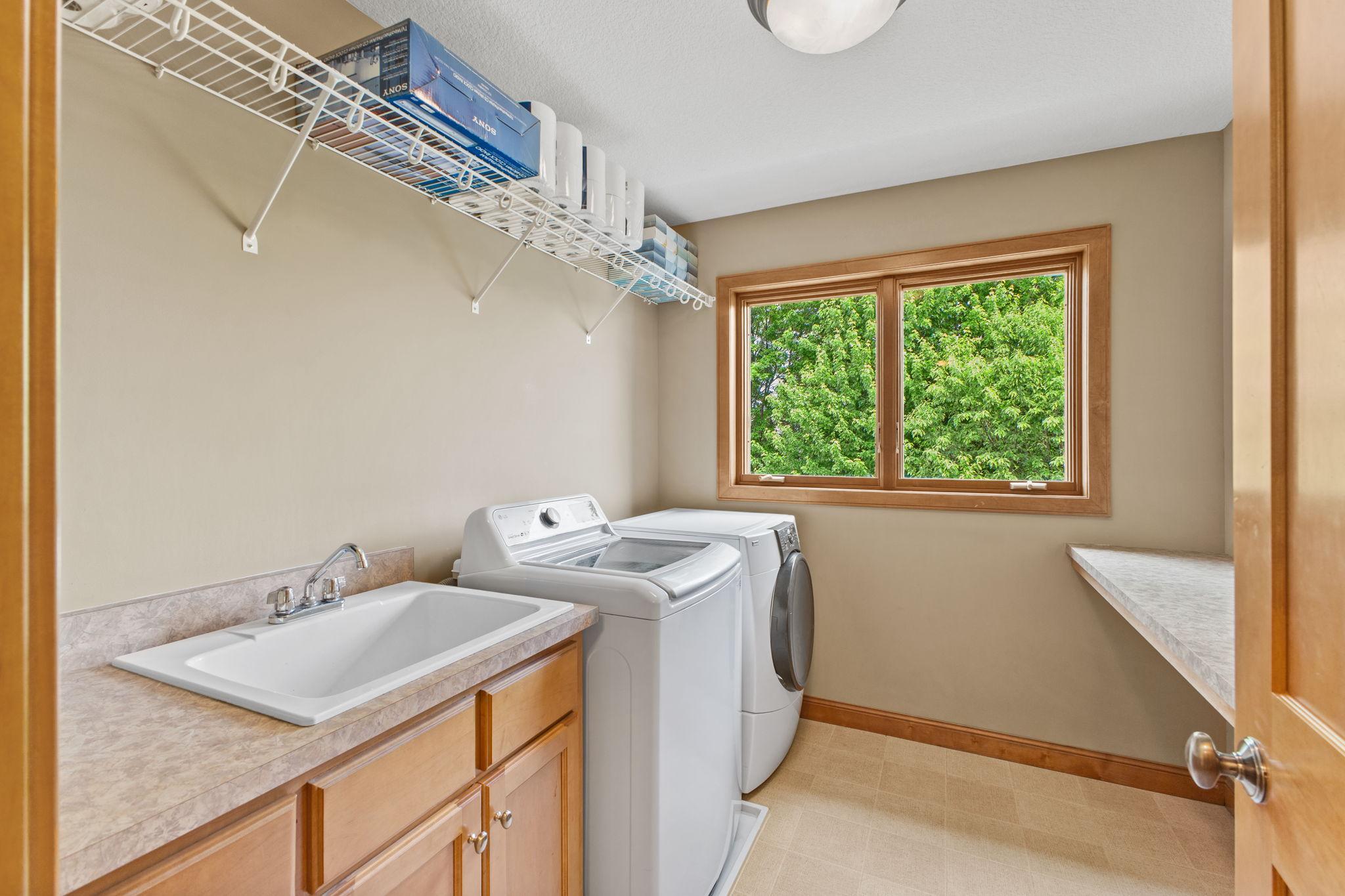 The conveniently located upper laundry with sink, window, hanging space and a huge folding area!