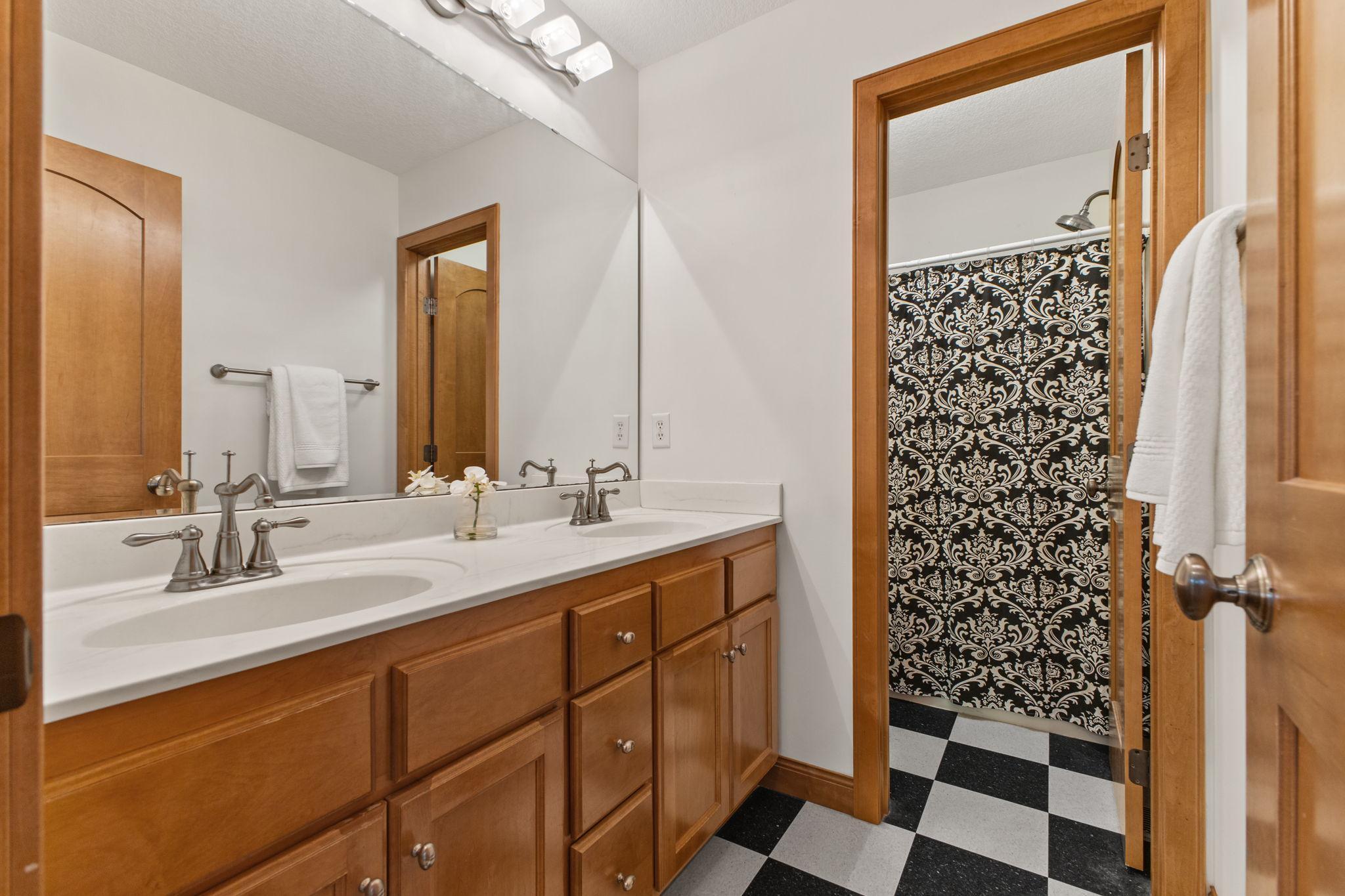 Main bathroom on upper level with dual sinks and private shower area for busy mornings.