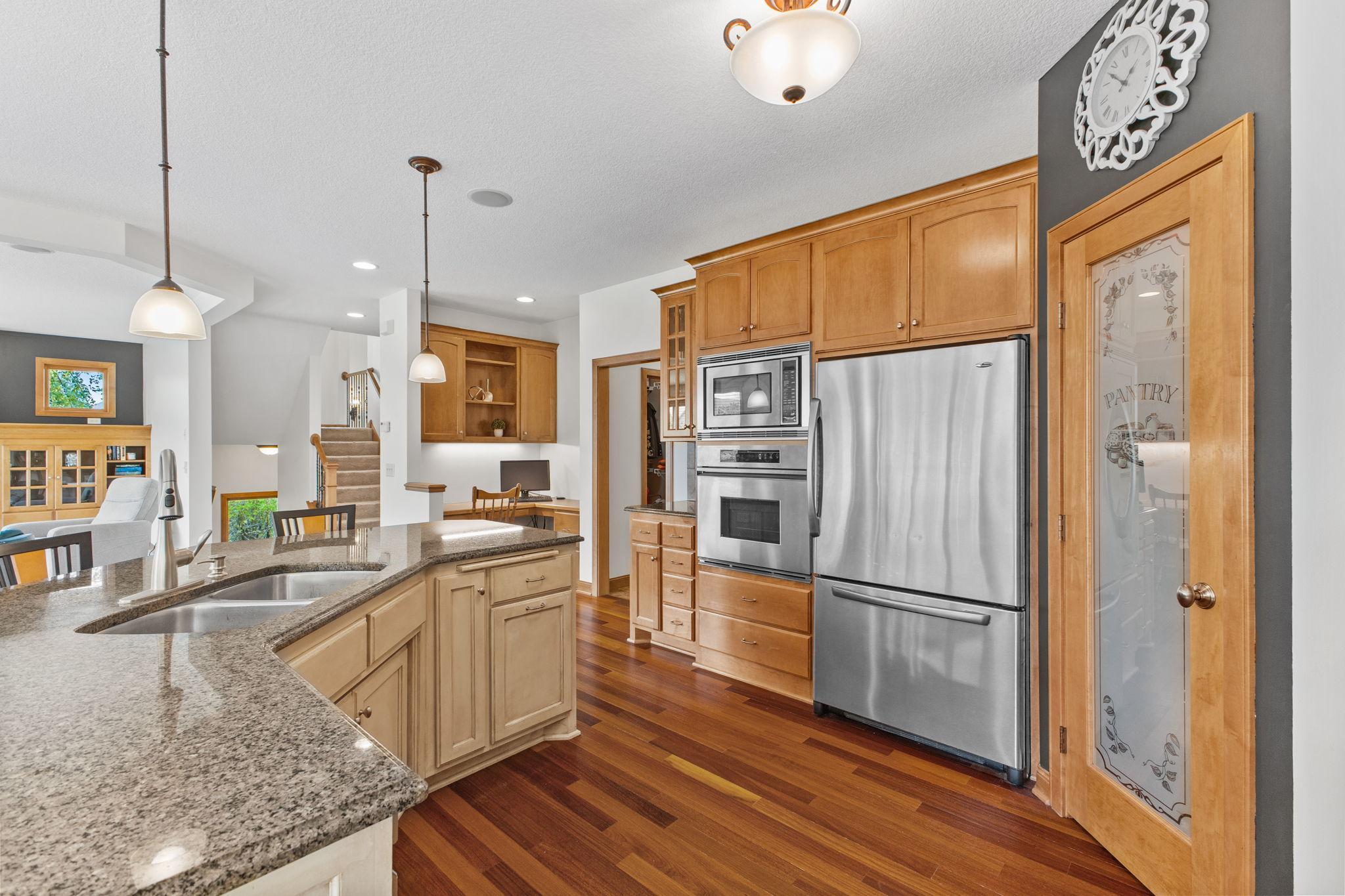 The designer finish on the center island offers a stylish accent to the warm tones of the natural hardwood floor and cabinets. Enjoy granite counters, SS appliances and endless storage!