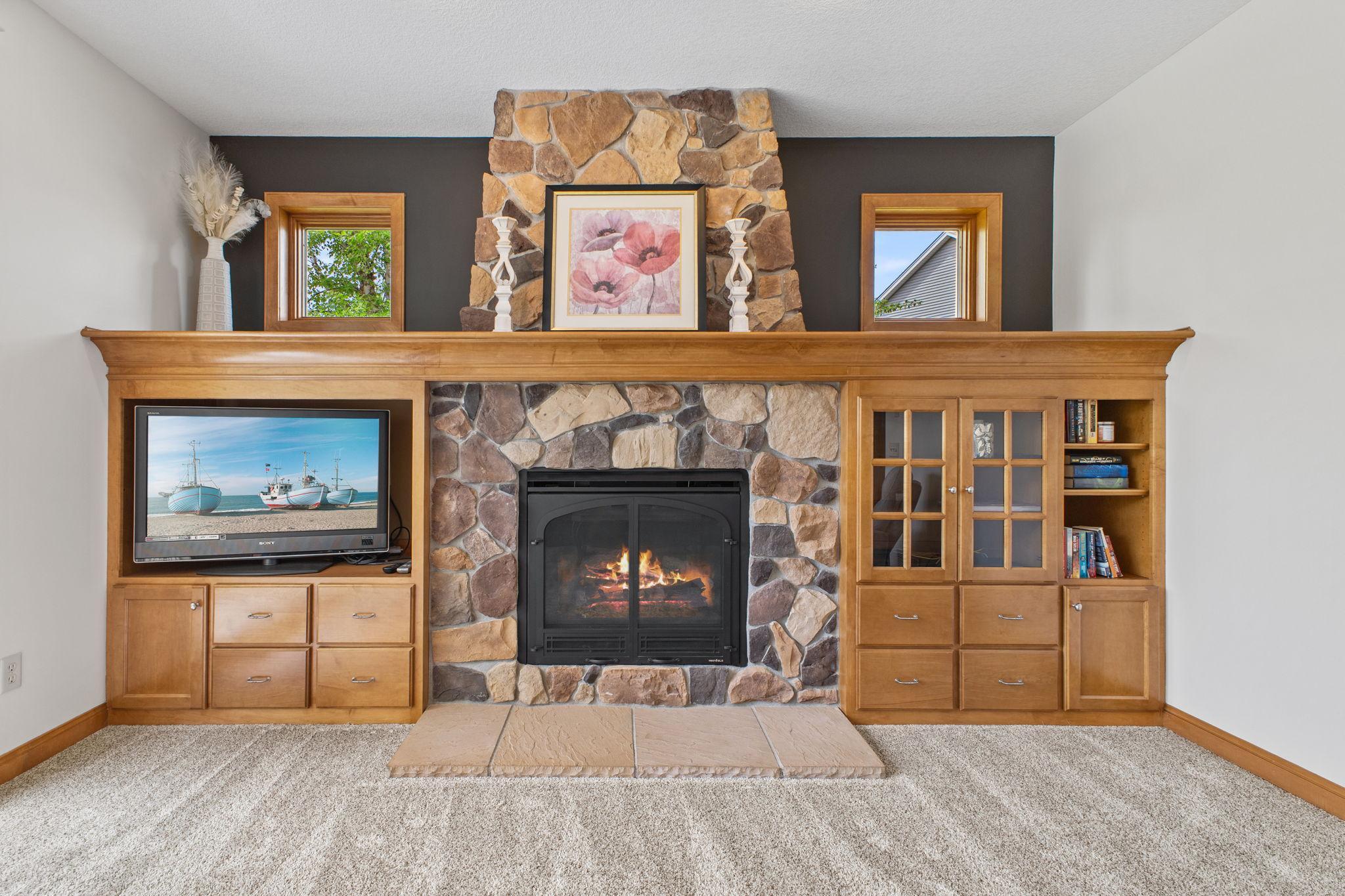 Then, there is this dramatic focal point wall with custom built-in cabinetry, a stone fireplace and beautifully placed transom windows.