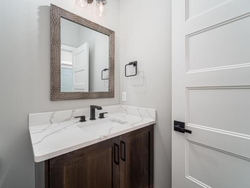 Main level 1/2 bathroom w/quartz countertops & black fixtures. Maybe you're a nickel or bronze/gold type of a person....no problem, switching up the plumbing and handles/pulls to another color-look is SIMPLE and can be incorporated throughout
