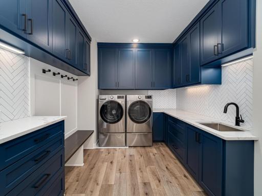 #Stunning and Practical! Checkout the heringbone tile backsplash, paneled walls, both upper and lower enamled cabinests with quart counter-tops in this Laundry/Mud/Back-Entryway off the garage. It's located near the primary owner's suite too!
