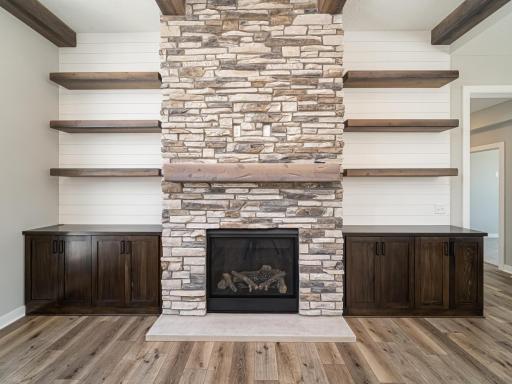 This stacked stone wrapped around the gas-burning fireplace goes floor to ceiling with a lower landing and upper mantel. Shiplap walls and floating shelves keep this area feeling airy while also serving as the mounting area for the TV too.