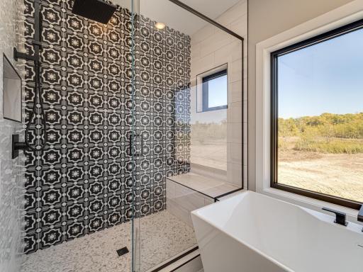 Glass envelopes the beautiful walk-in shower with designer tile, bench and upper transom window.