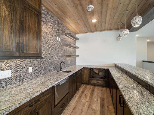 Tile and undermount lighting...just a few things that make this lower level bar area special. Add a pool one day and you'll come right in off the backyard patio area into the bar to eat lunch, grab drinks or have it the kids area for food/drink.