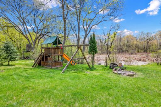 A firepit and playset at the far rear of the property