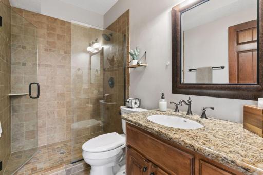 The lower level bath features a large tile shower, tile floors and granite countertops.
