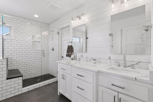 The fully remodeled primary bath offers a spa-like retreat with gorgeous quartz countertops, a furniture-style vanity, an oversized tile shower, soaking tub, and private toilet room. The bathroom leads to the walk-in closet.