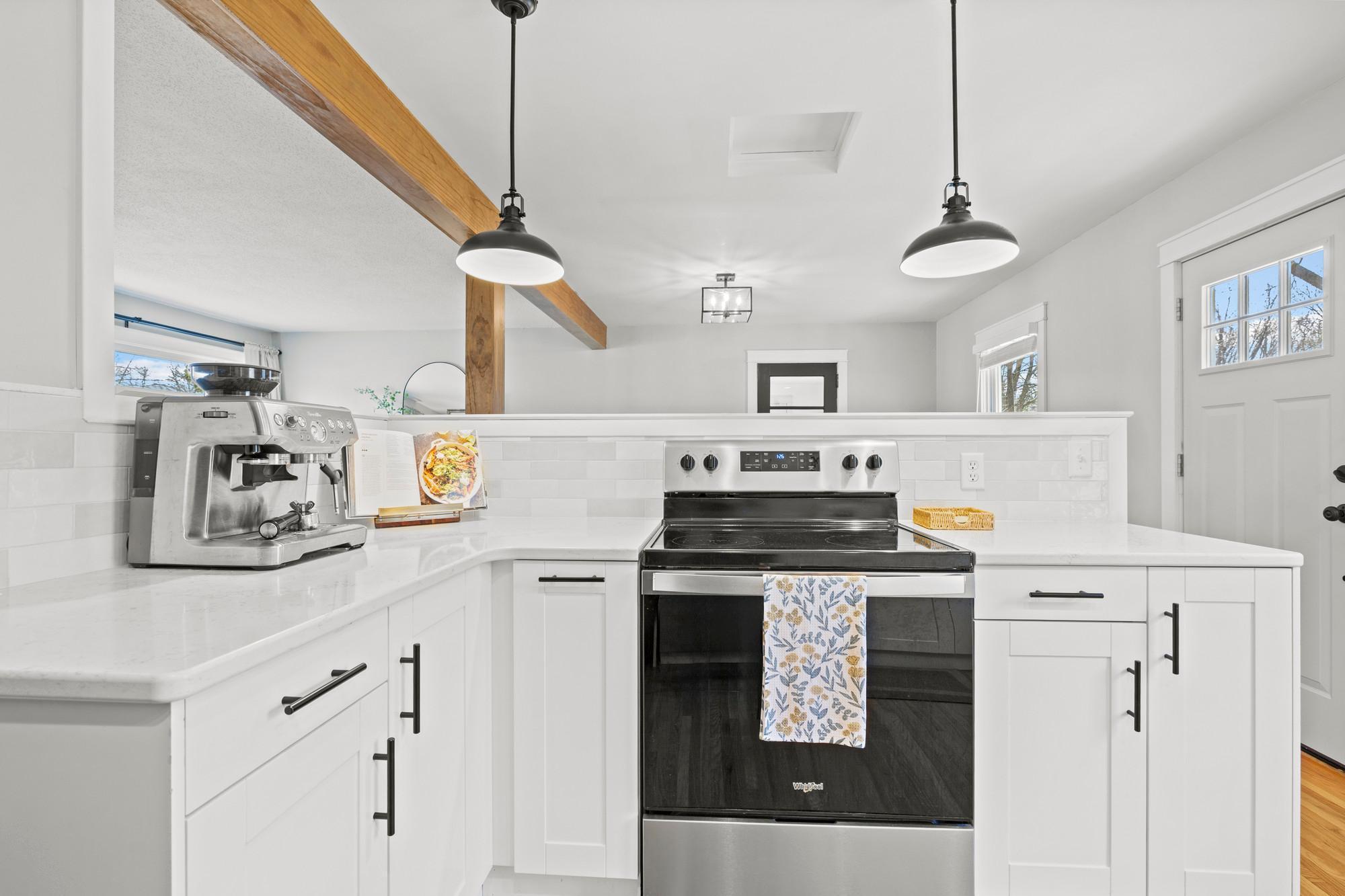 Kitchen full of updates - all new cupboards, new quartz countertops and tile backsplash, updated appliances, removed wall for open layout, and new lighting