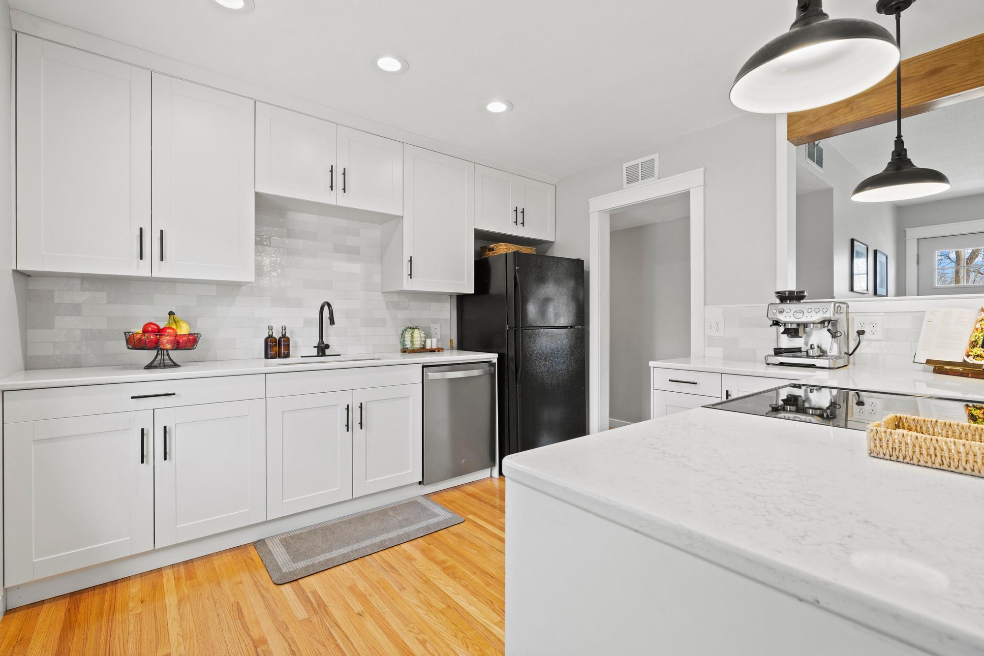 Kitchen full of updates - all new cupboards, new quartz countertops and tile backsplash, updated appliances, removed wall for open layout, and new lighting