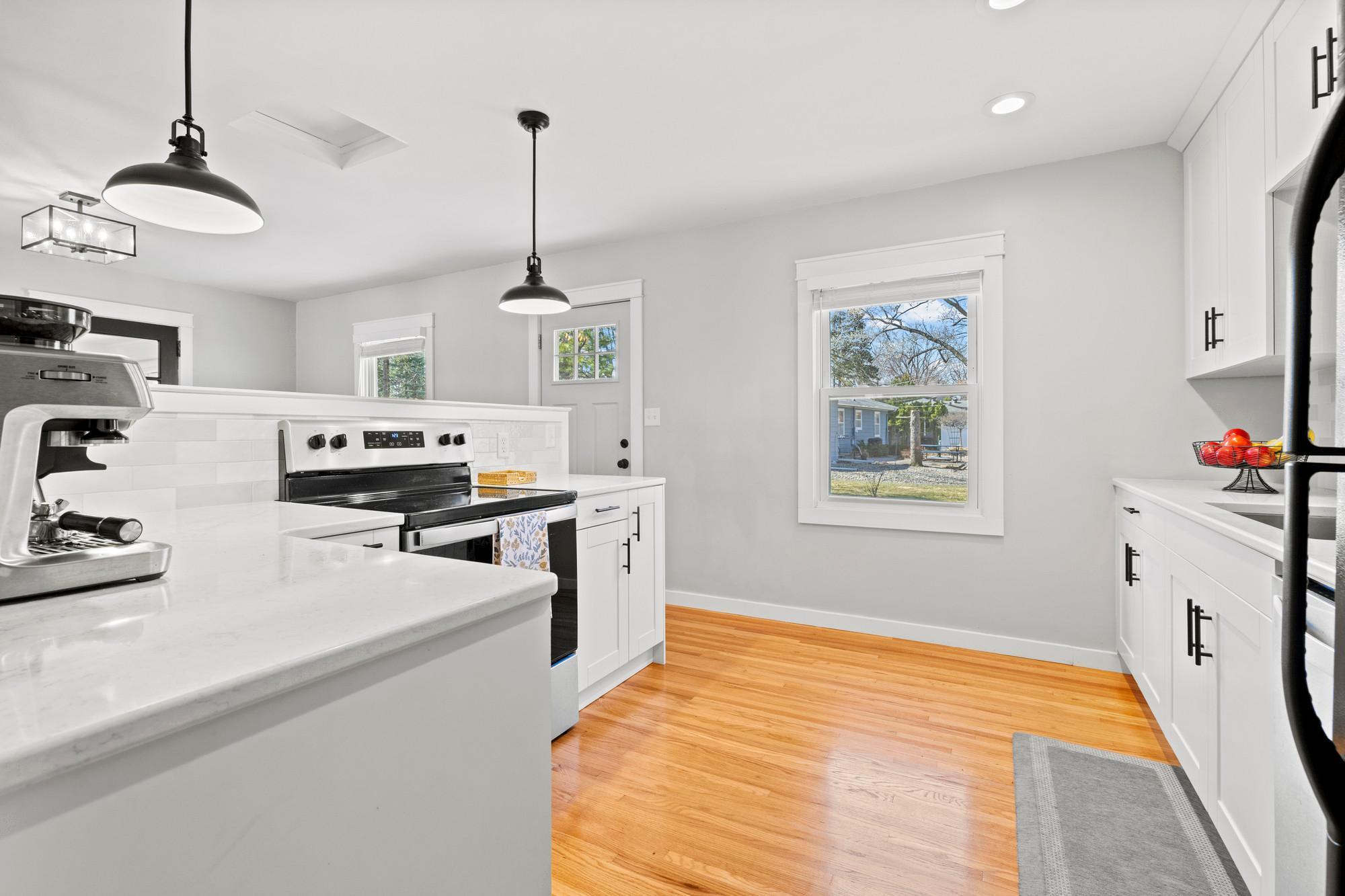 Kitchen full of updates - all new cupboards, new quartz countertops and tile backsplash, updated appliances, removed wall for open layout, and new lighting