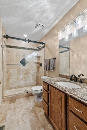 Main floor 3/4 bath updated with Travertine tile, quartz counter and updated doors and fixtures