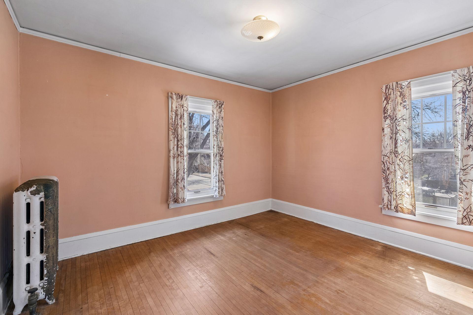 The spacious second upper level bedroom with hardwood floors, overhead lighting, and natural light from two windows.