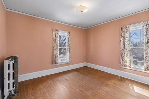 The spacious second upper level bedroom with hardwood floors, overhead lighting, and natural light from two windows.